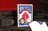 A deck of Blank Faced Blue Backed Bicycle Cards on a stone floor with a glowing red cave behind. 