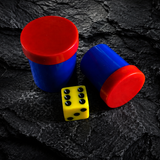 Two blue dice cups with red lids and a yellow die on a dark stone surface