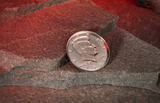 An Expanded Half Dollar Shell for Coin Magic on. a stone floor with a glowing red cave background. 