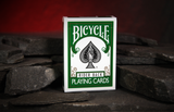 A deck of green Bicycle Playing Cards with a Rider Back standing on grey slate with a warm red background. 