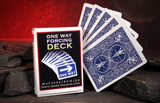 A Bicycle card deck labeled 'ONE WAY FORCING DECK' stands beside five fanned playing cards showing blue Bicycle back designs, set on dark stones against a glowing red cave background.