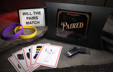 Playing cards depicting clothes along with two coloured wrist bands and a memory stick for the magic trick Paired in a cave with glowing red background. 