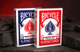 Two Bicycle Special ESP Playing Cards decks standing upright on dark stones against a glowing red cave background. 