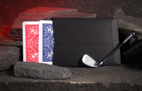 A black envelope with a silver golf club resting beside it, shown beside two playing cards (red and blue backs) on dark stone blocks with a red glowing cave background behind them.